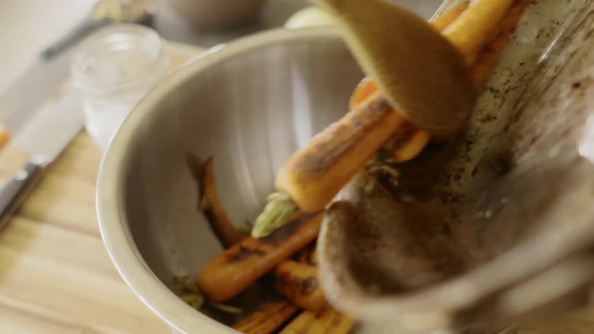 Fried carrots being poured on a bowl from a pan in kitchen