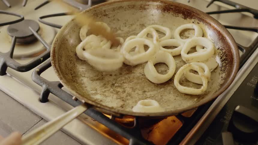 Onion rings frying on pan over a gas stove
