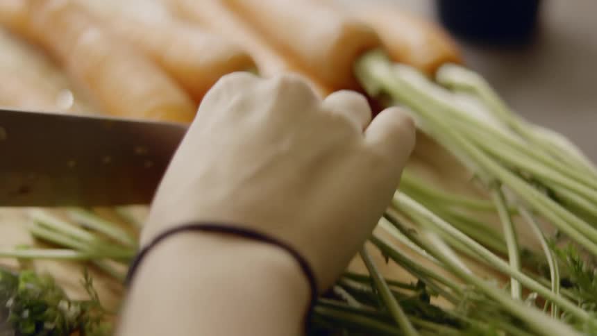 A woman is using a knife to cut carrots at home