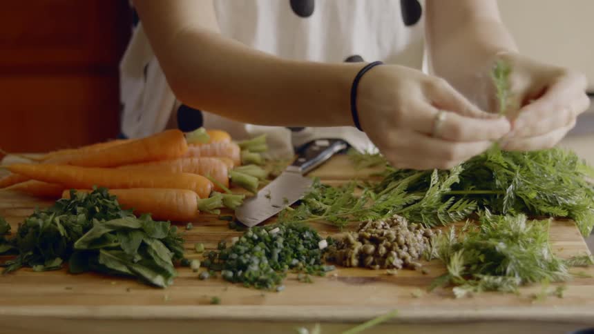 A woman preparing vegetables on a cutting board