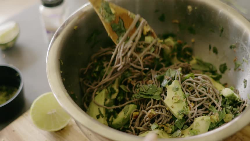 A woman stirs a bowl of pasta