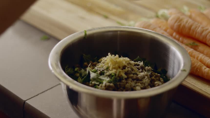 Person grinds pepper to season food in bowl