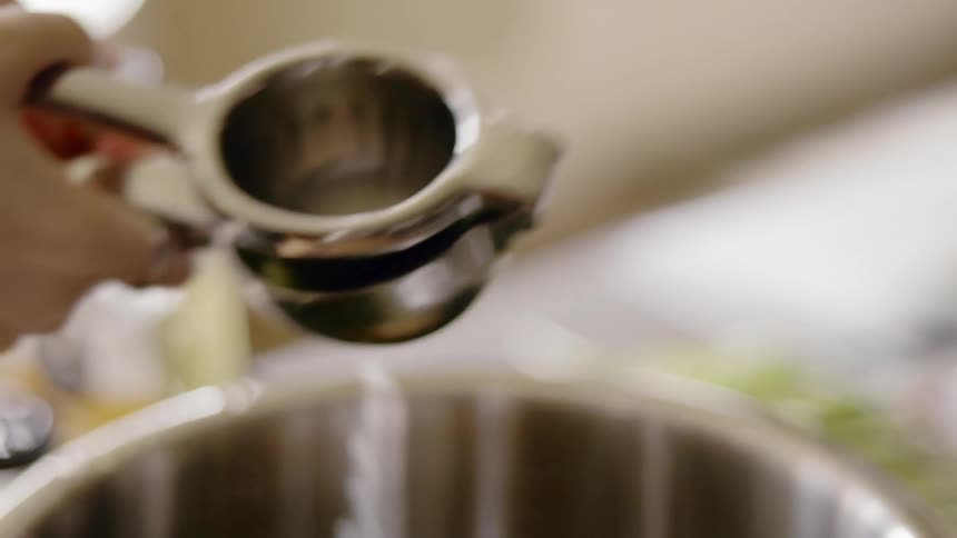Woman squeezes juice from lime into bowl