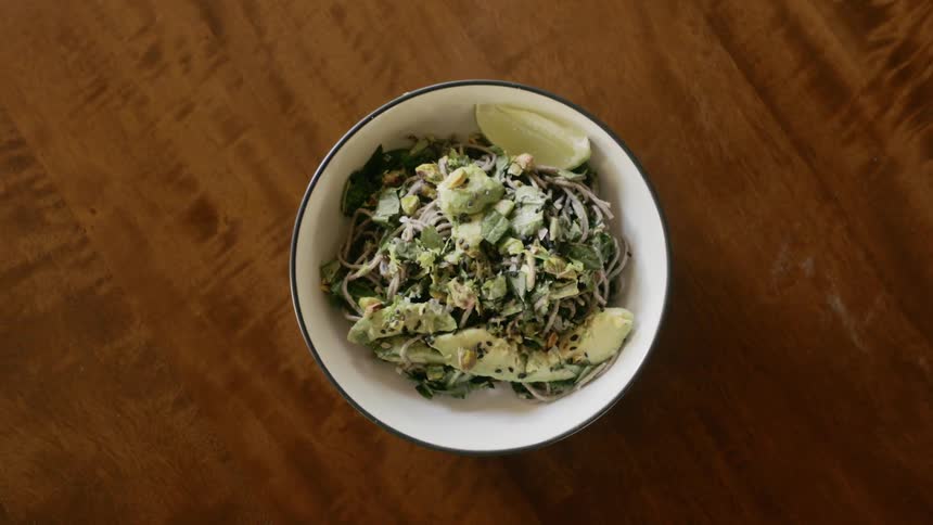 A bowl with a vegetarian dish is set on a wooden table