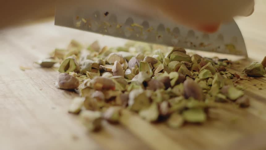 Person chops ingredient coarsely on wooden chopping board
