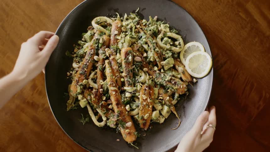 A womans hands taking a dish of food from a table