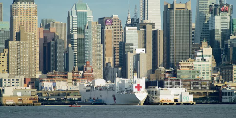 The usns comfort docked with the new york city skyline behind it