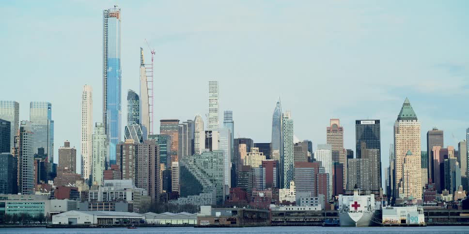 Skyscrapers of varying heights fill the skyline of a city along the shore