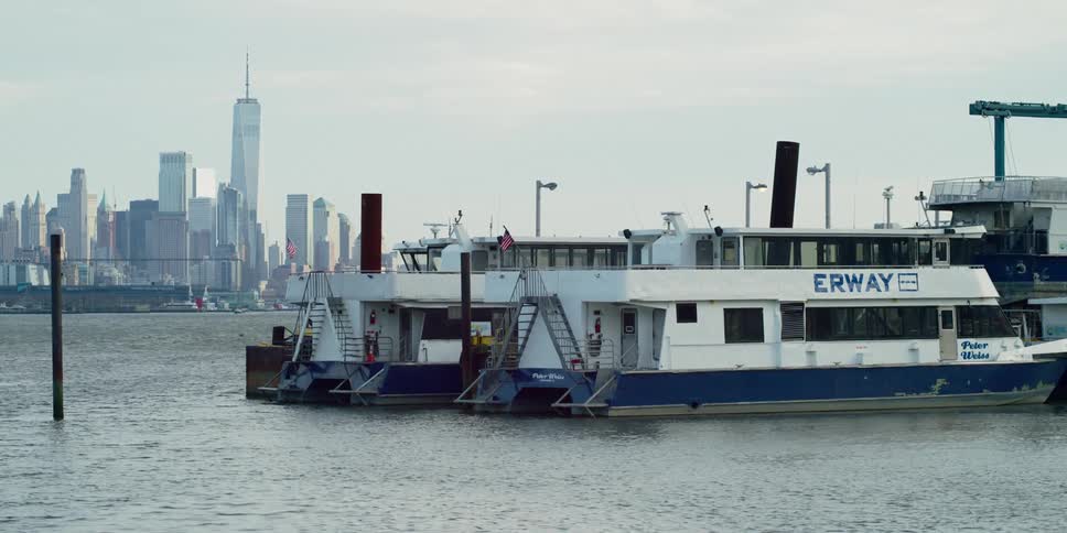 Water vessels on the water with a city skyline in the background