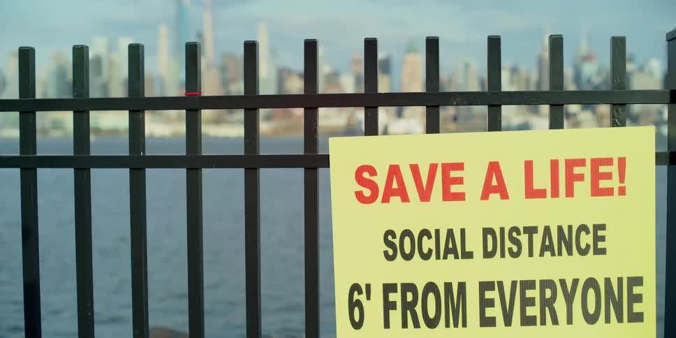 A sign on a fence tells people to stay six feet away from each other