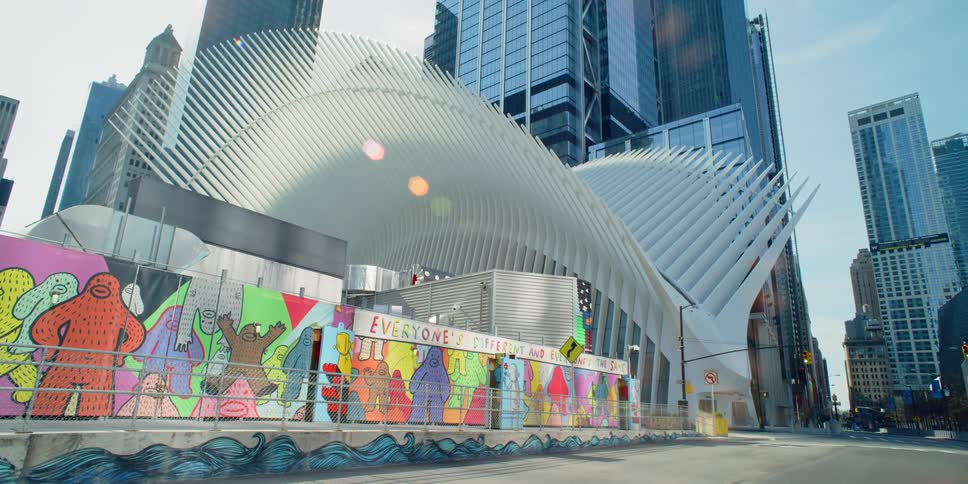Sculpture with ribs spread like wings hangs over painted wall near skyscrapers downtown