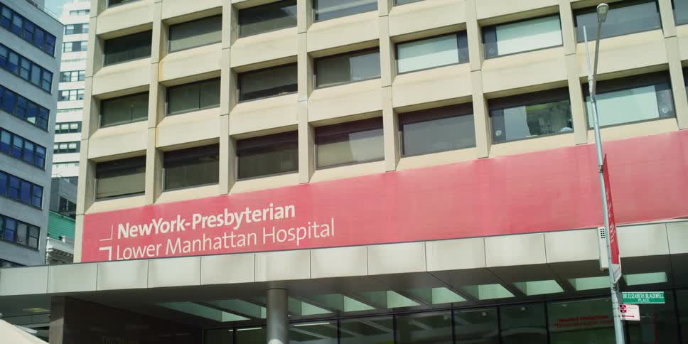 A woman walks past the front of a new york city hospital