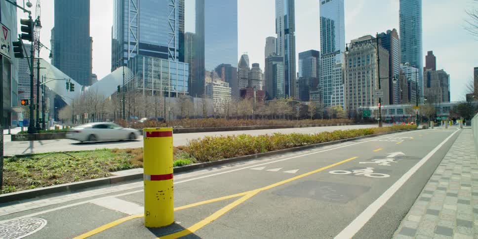 A cyclist rides on a path next to cars driving down a road