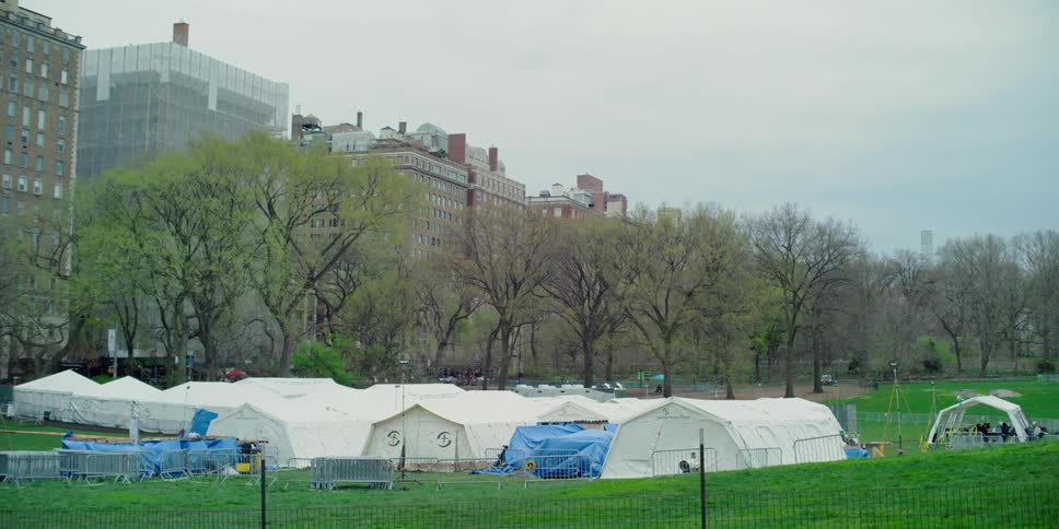 Emergency tents and shelter are set up on the grass of a city park