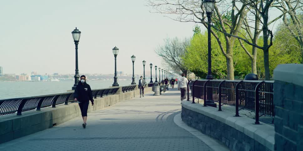 People walk along waterfront path across from downtown skyscrapers