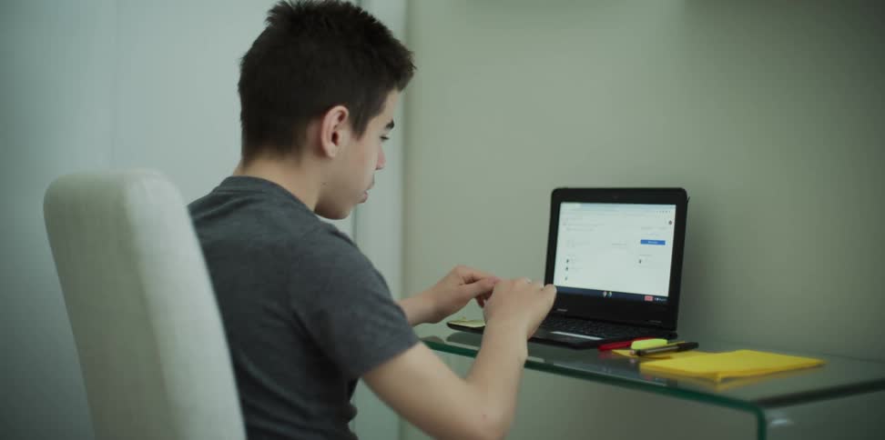 A young boy plays on his laptop