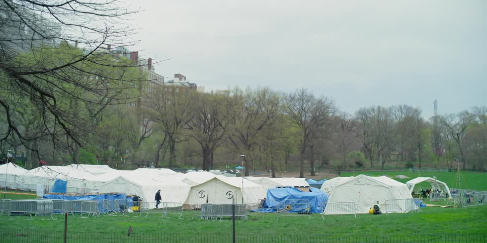 People walk around the large white hospital tents set up in central park