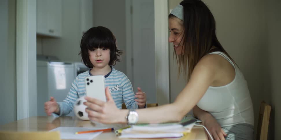 Mother and child watch mobile phone sitting at table