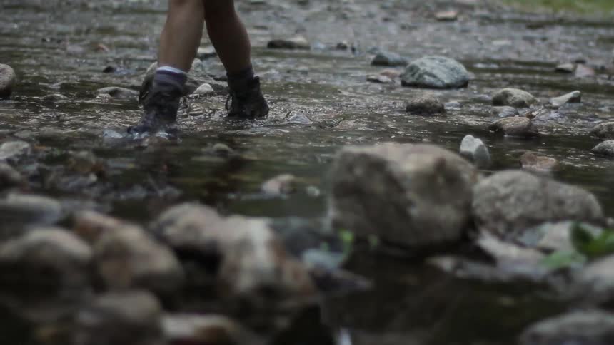 People walking through very shallow water as it flows between numerous rocks