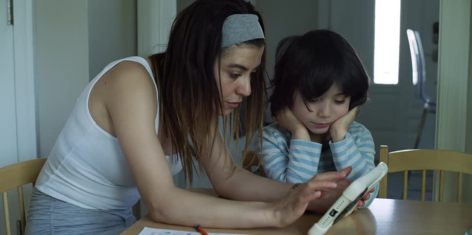 Woman types on tablet while son waits for her to finish