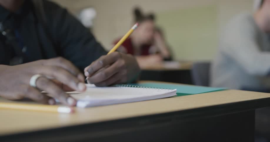 Student in classroom filling exam with pencil in classroom