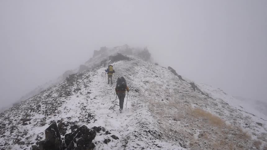 People are climbing up a mountain during heavy snow