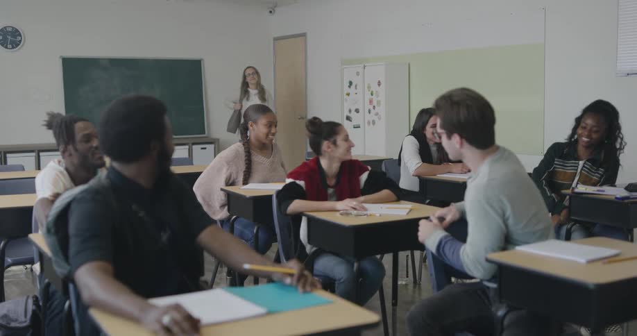 Students preparing for class as the teacher enters the room