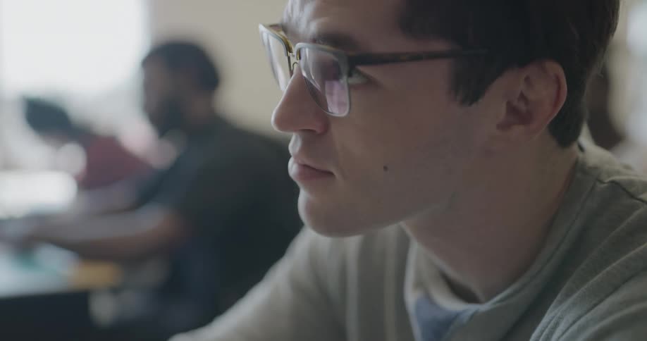 Close up of male student taking notes in a classroom