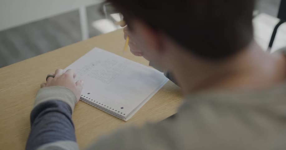 A student takes a notebook out of his backpack and writes in it