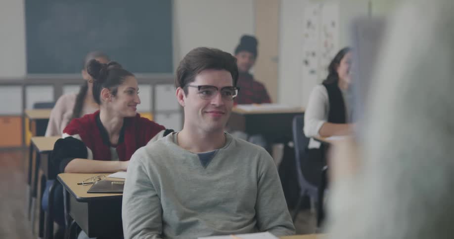 Students smile and talk to each other and the teacher in a classroom