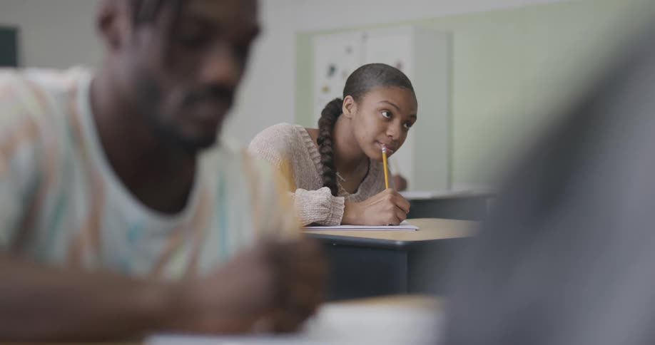 Male and female student taking notes in a classroom