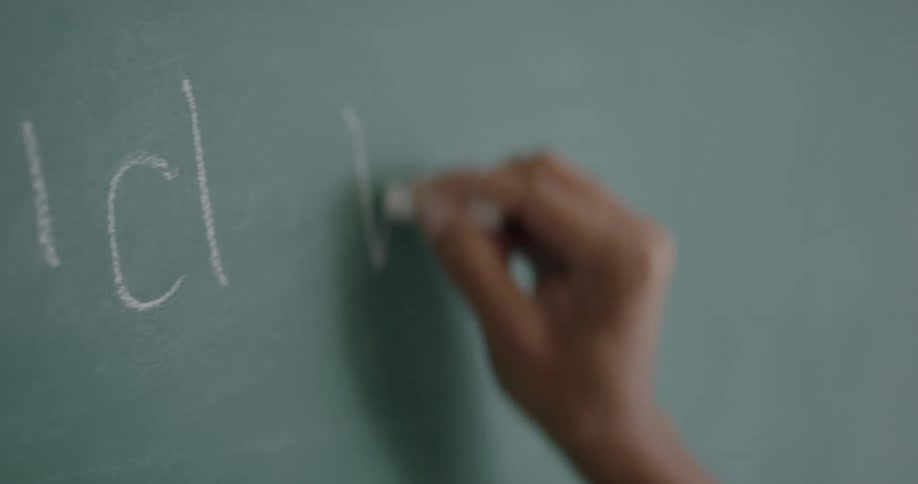 Teacher writing on blackboard with chalk