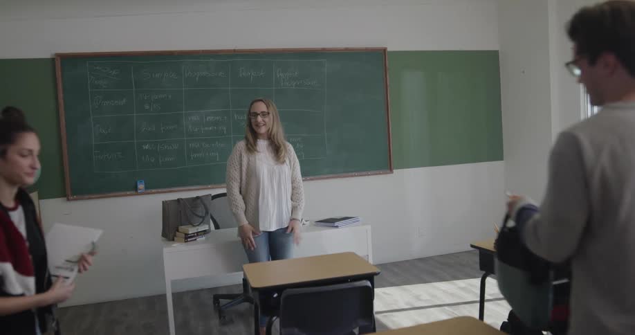 Teacher greets students as they enter classroom and find seats