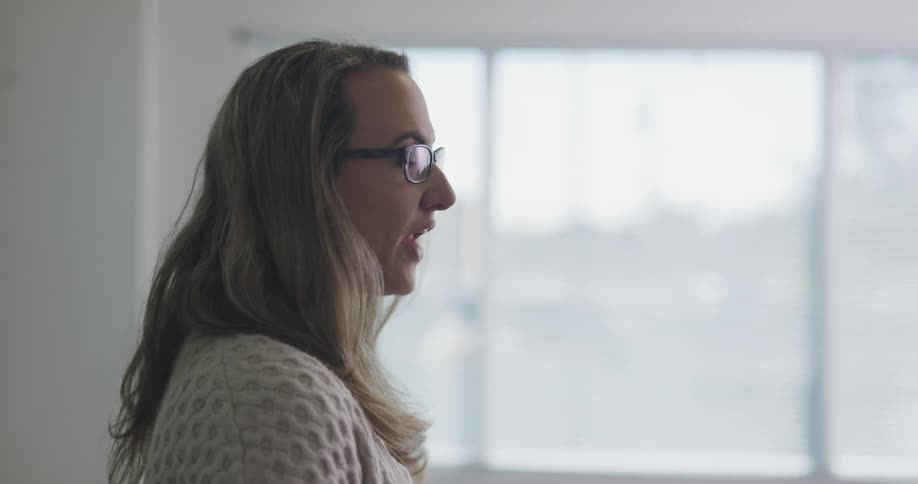 A teacher talks to students in a classroom with sunlight coming through the window