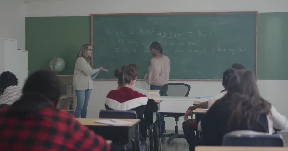 A student writes on the chalkboard in a classroom