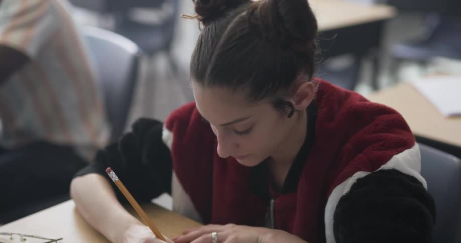 A girl looks at a fellow student before taking notes in class