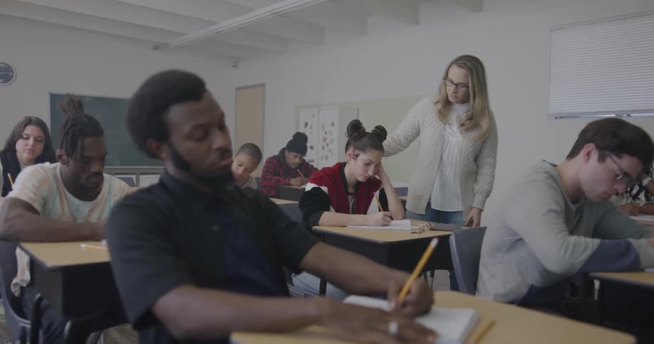 A teacher is walking around a classroom full of students
