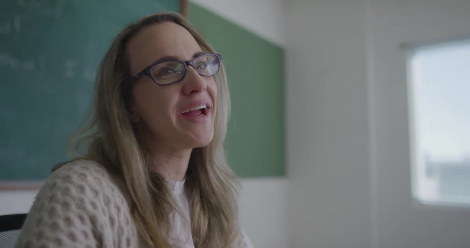 A teacher talks at the front of her classroom