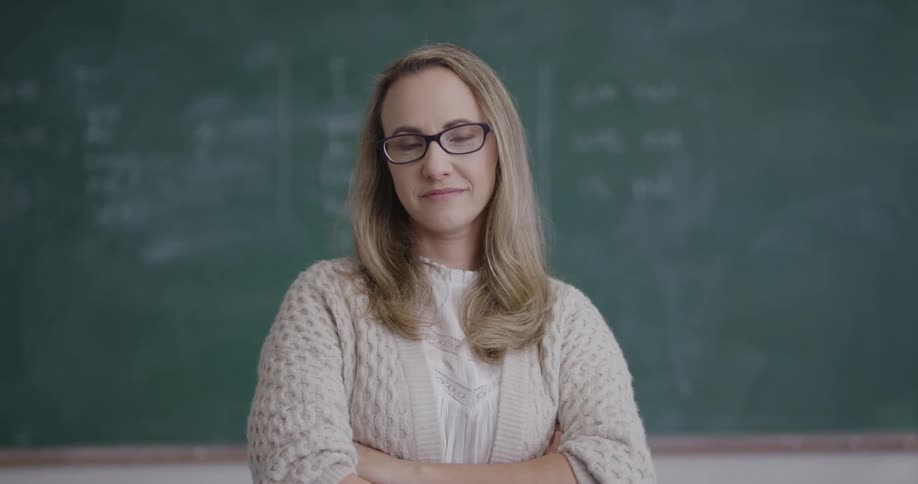 Teacher standing in front of blackboard in classroom