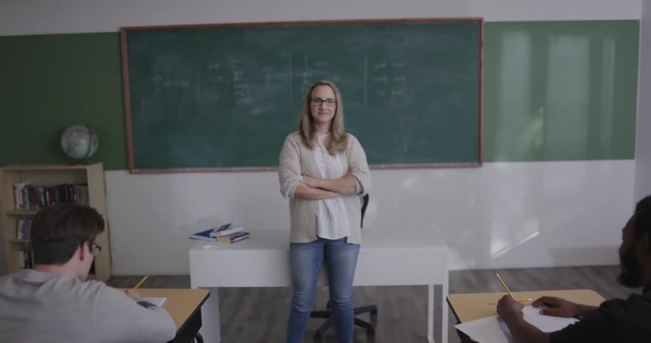 A teacher stands at the front of a classroom as students work
