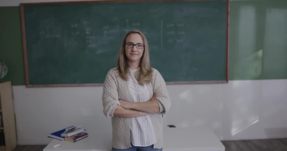 Instructor posing in classroom as camera zooms out and students look back