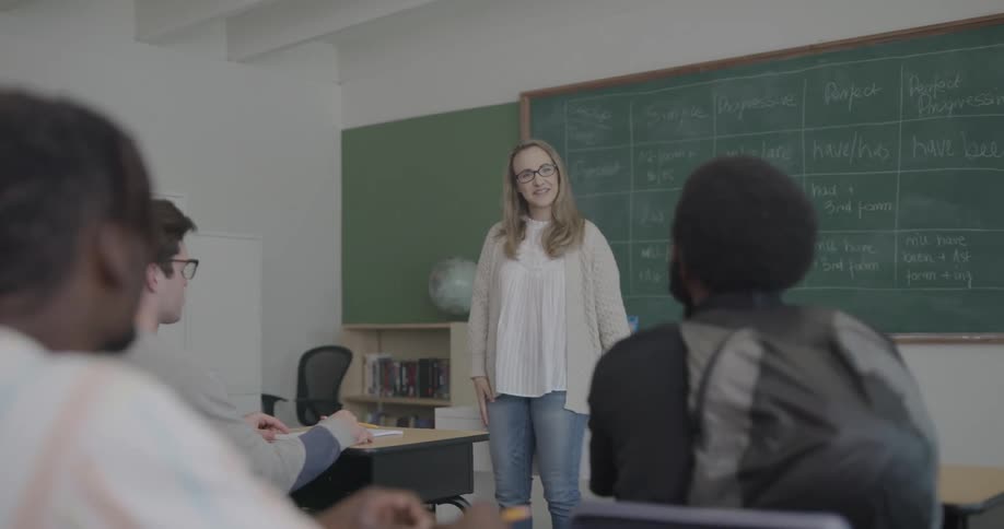 A student turns and talks to another student as his university professor teaches class