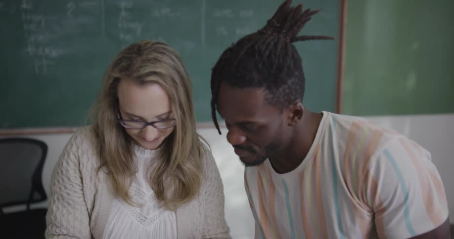 A man and woman are sitting in a classroom and talking