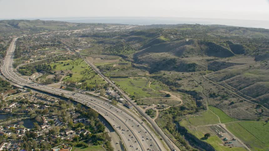 Aerial view of a busy freeway by the mountains and ocean