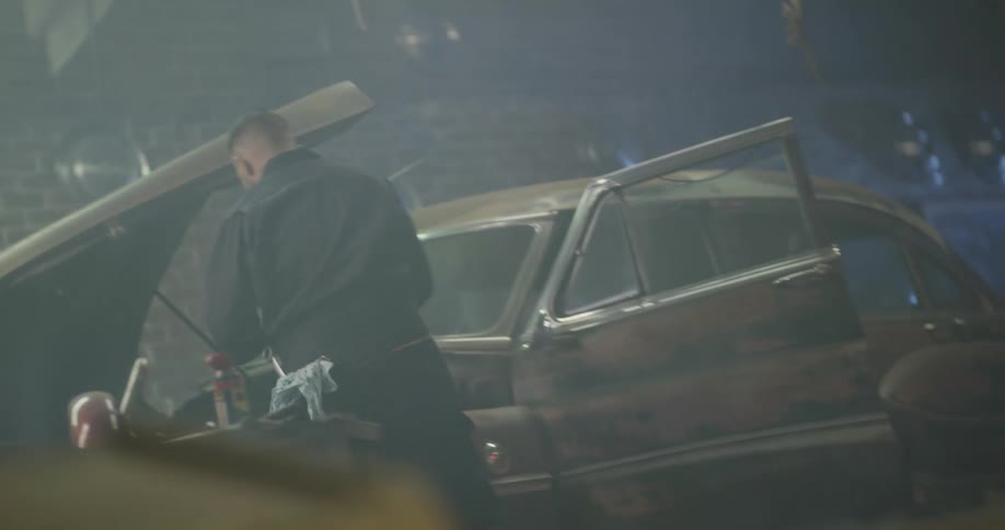 A mechanic gathering tools and working underneath a car hood