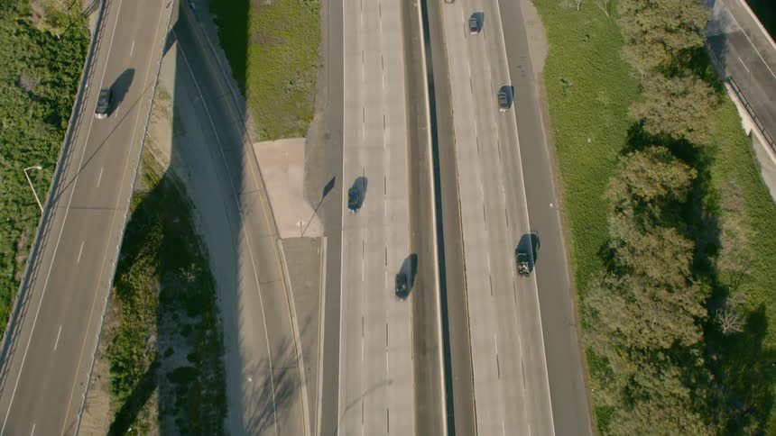 Cars travel on multi lane highways loops and overpasses on a sunny day