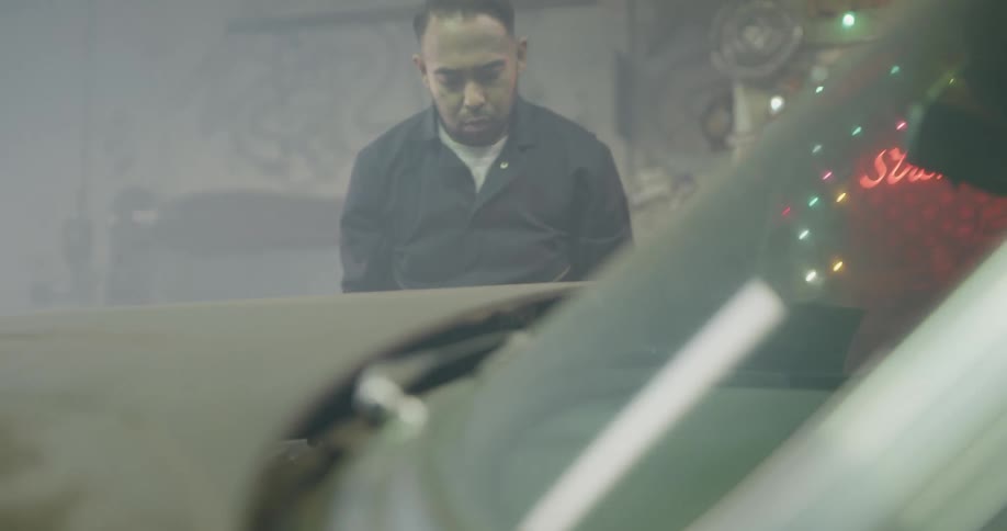 A mechanic closes the hood of a car