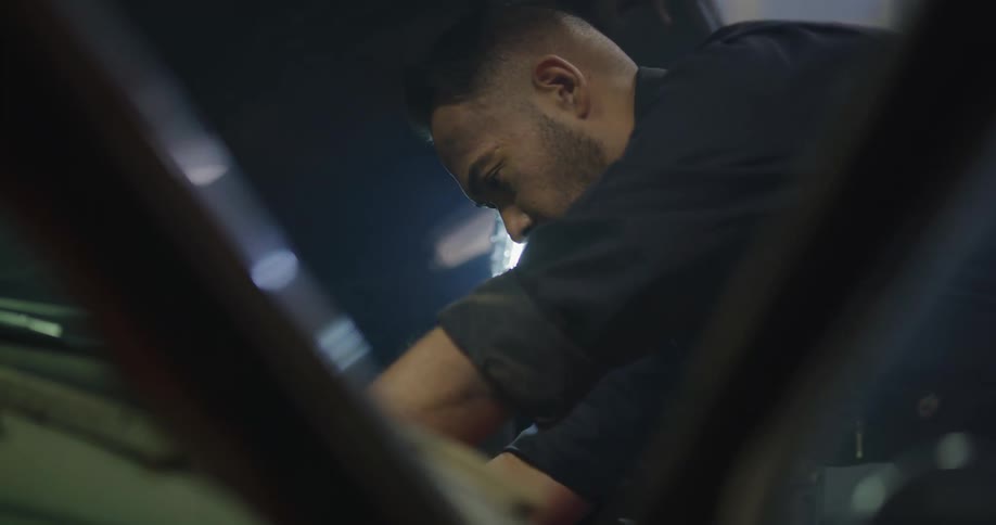 Mechanic works on vintage car engine in workshop