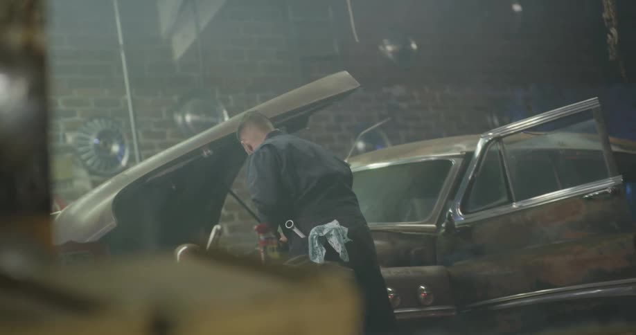A mechanic works under the hood of a vehicle in an auto shop