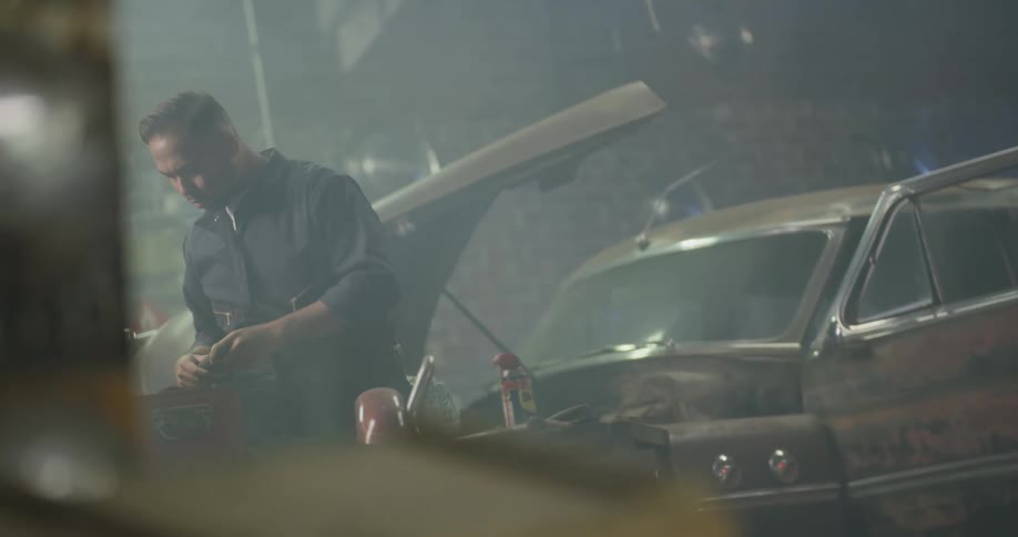 A mechanic works under the hood of a vehicle in an auto shop